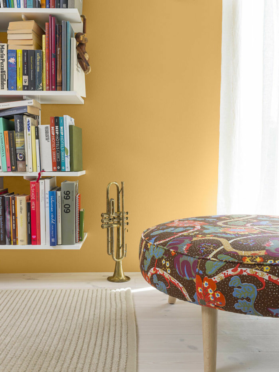 Foto: <a href="http://www.beckers.se/inspiration-och-kulor/inspirationsbilder" target="_blank" rel="noopener">Beckers</a> Gulmålad vägg, bokhylla och mönstrad pall