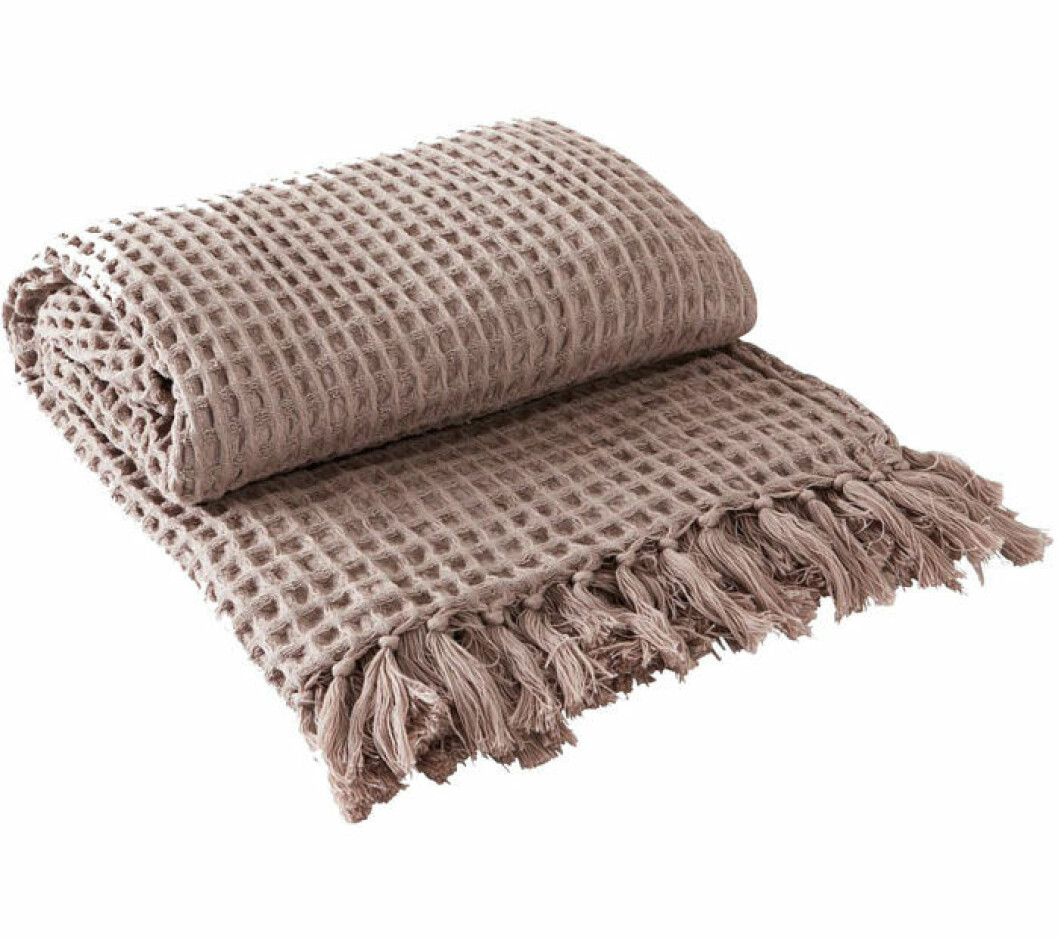 En beige pläd som gör vardagsrummet mysigare