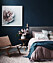 Sovrum med blåa väggar och rosa pioner i en vas på sängbordet