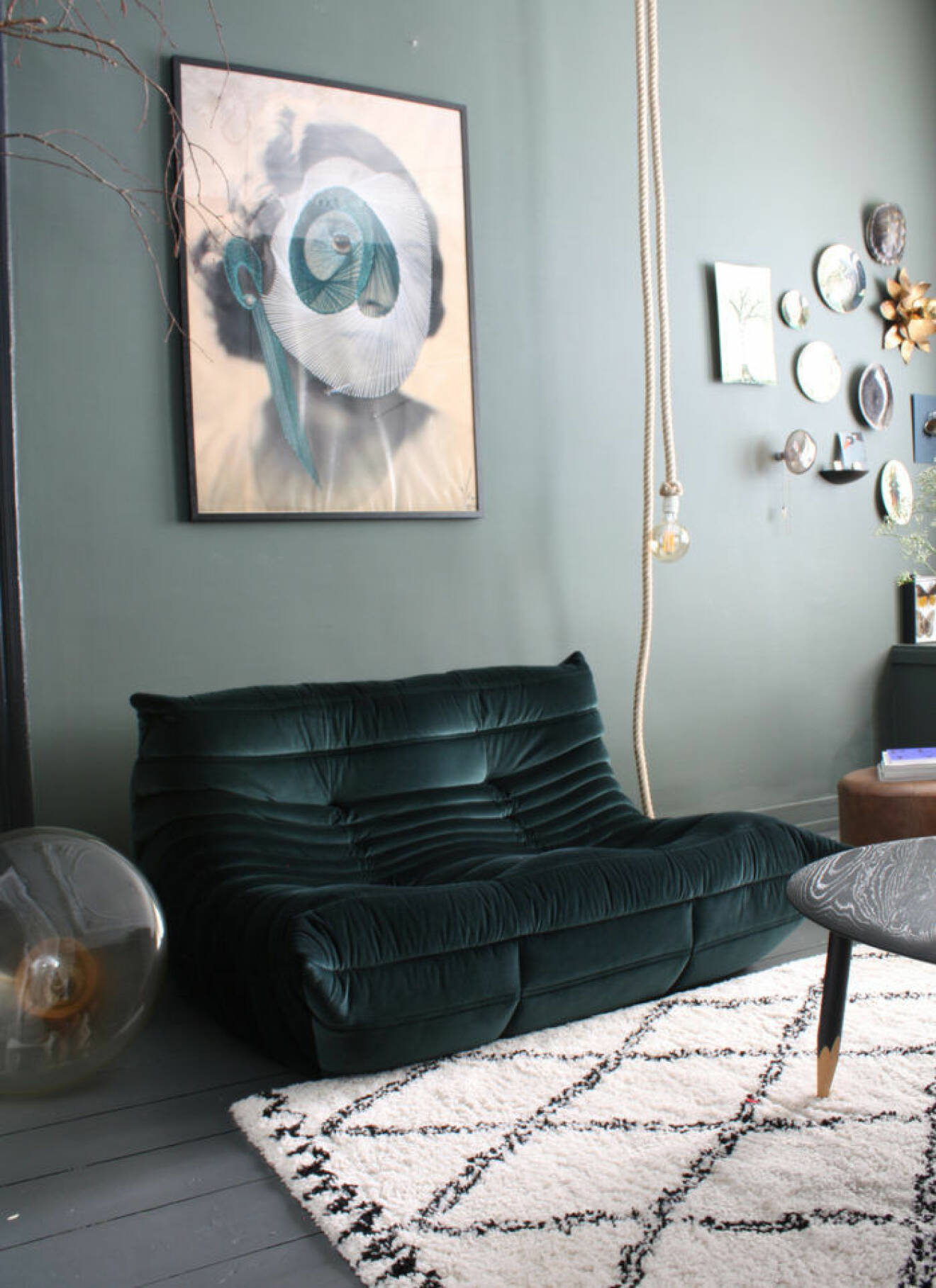 Vardagsrum med soffa i grön sammet och ljusgröna väggar.