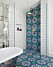 Färgstarkt, mönstrat kakel på golvet i ett badrum löper upp på ena duschväggen.