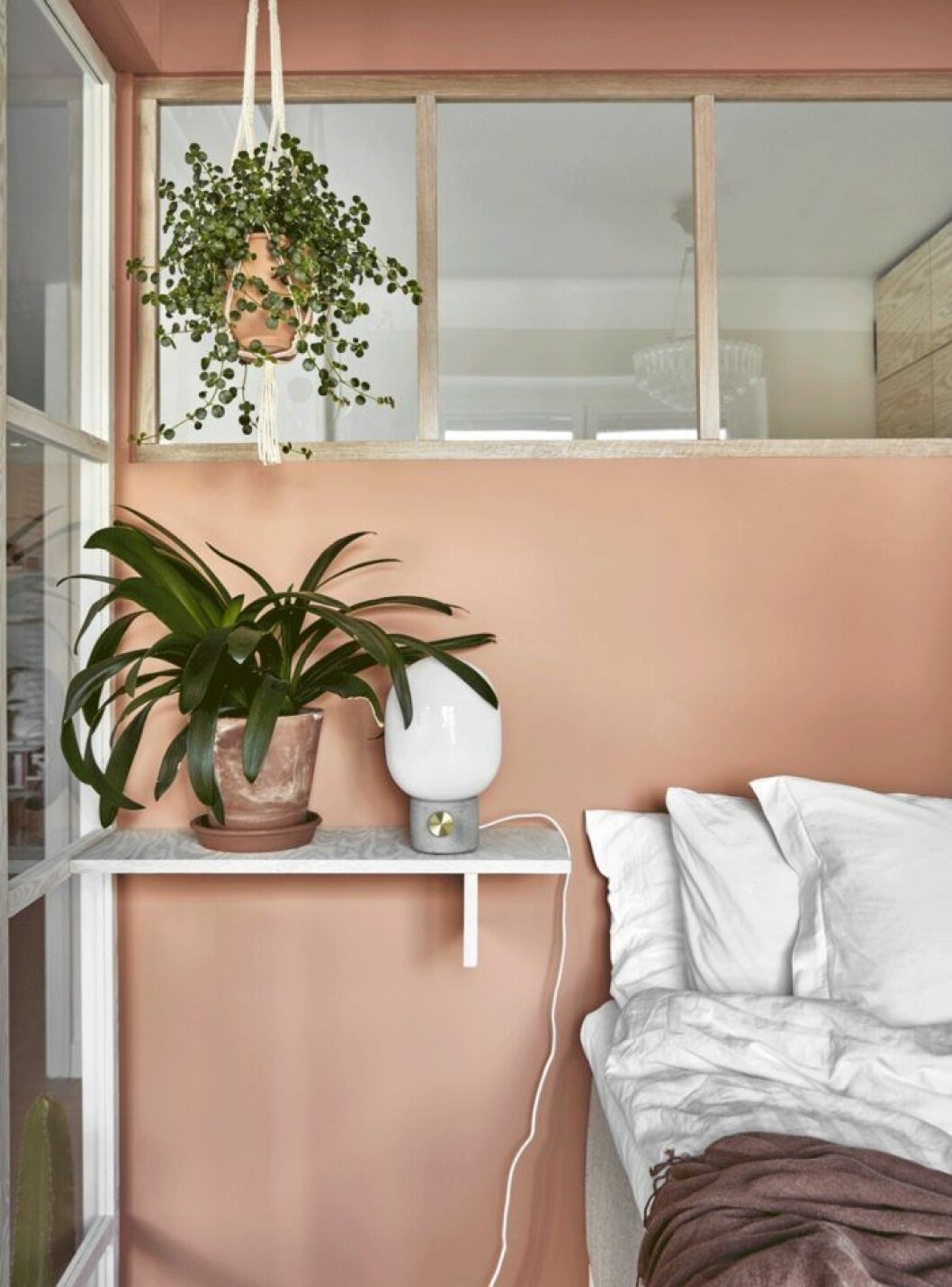 En hylla istället för sängbord i ett compact living-sovrum.