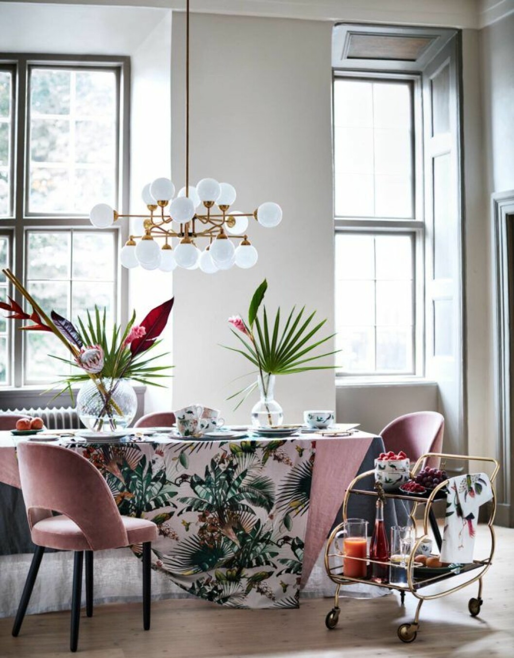 Foto: <a href="http://www2.hm.com/sv_se/home.html" target="_blank" rel="noopener">H&M Home</a> Matplats med rosa stolar, drinkvagn i mässing, lampa i mässing och mönstrad bordsduk.