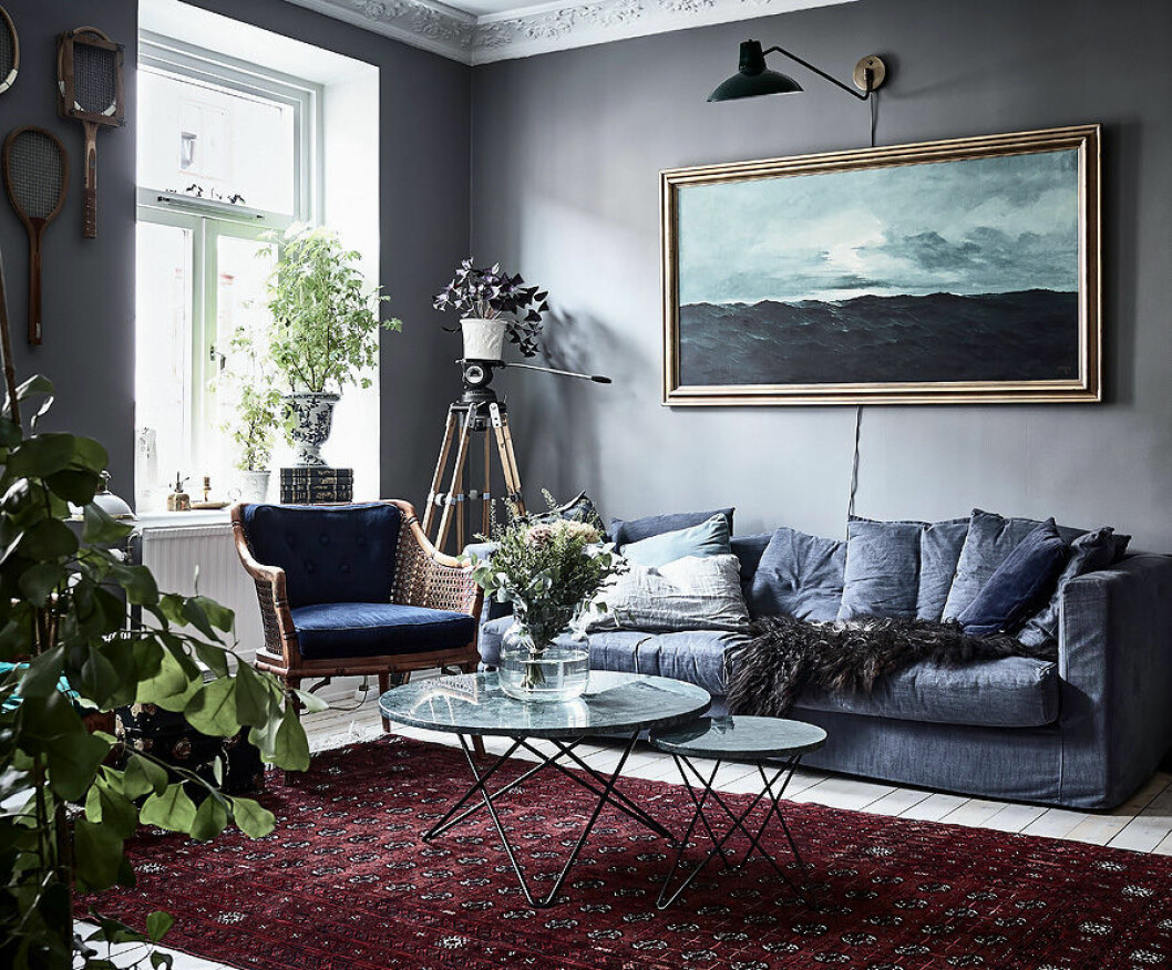 Foto: <a href="https://www.instagram.com/fotografanders/" target="_blank" rel="noopener">Anders Bergstedt</a> för <a href="https://www.instagram.com/entrancemakleri/" target="_blank" rel="noopener">Entrance mäkleri</a>/mäklare: Erika Bergholm Oljemålning och mörkgrå vägg. Persisk matta i rött och blå soffa.