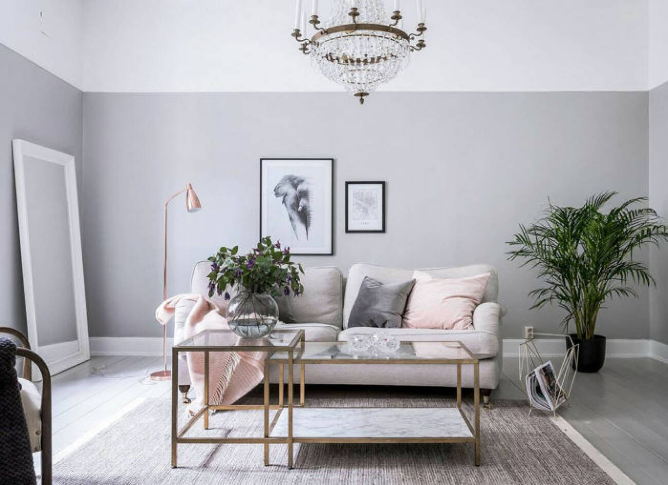 Ljusgrå väggar i vardagsrum med ljus soffa, kristallkrona och rosa prydnadskuddar.