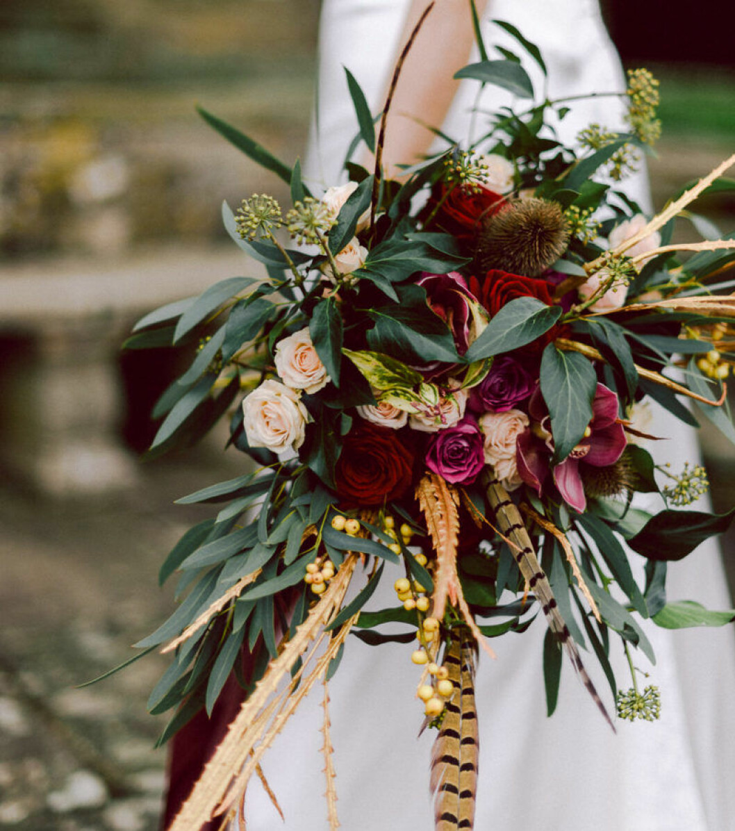 Foto via: <a href="https://www.wedding-venues.co.uk/wedding-ideas/2016/24-beautiful-winter-wedding-flowers" target="_blank" rel="noopener">Wedding venues</a> Röda blommor som en kontrast till den vita klänningen.