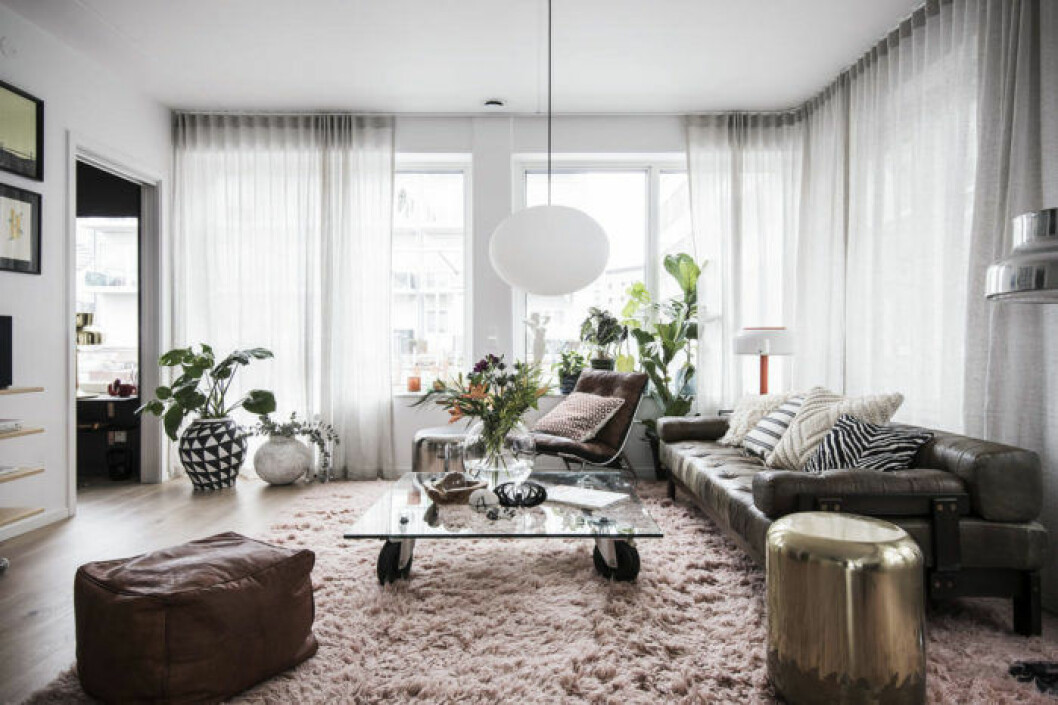 Foto: Elisabeth Daly för <a href="https://www.instagram.com/bosthlm_realestate/" target="_blank" rel="noopener">Bo Sthlm</a>/mäklare: Johanna Åhman Vardagsrum med rosa ryamatta och skinnsoffa samt sittpuff.