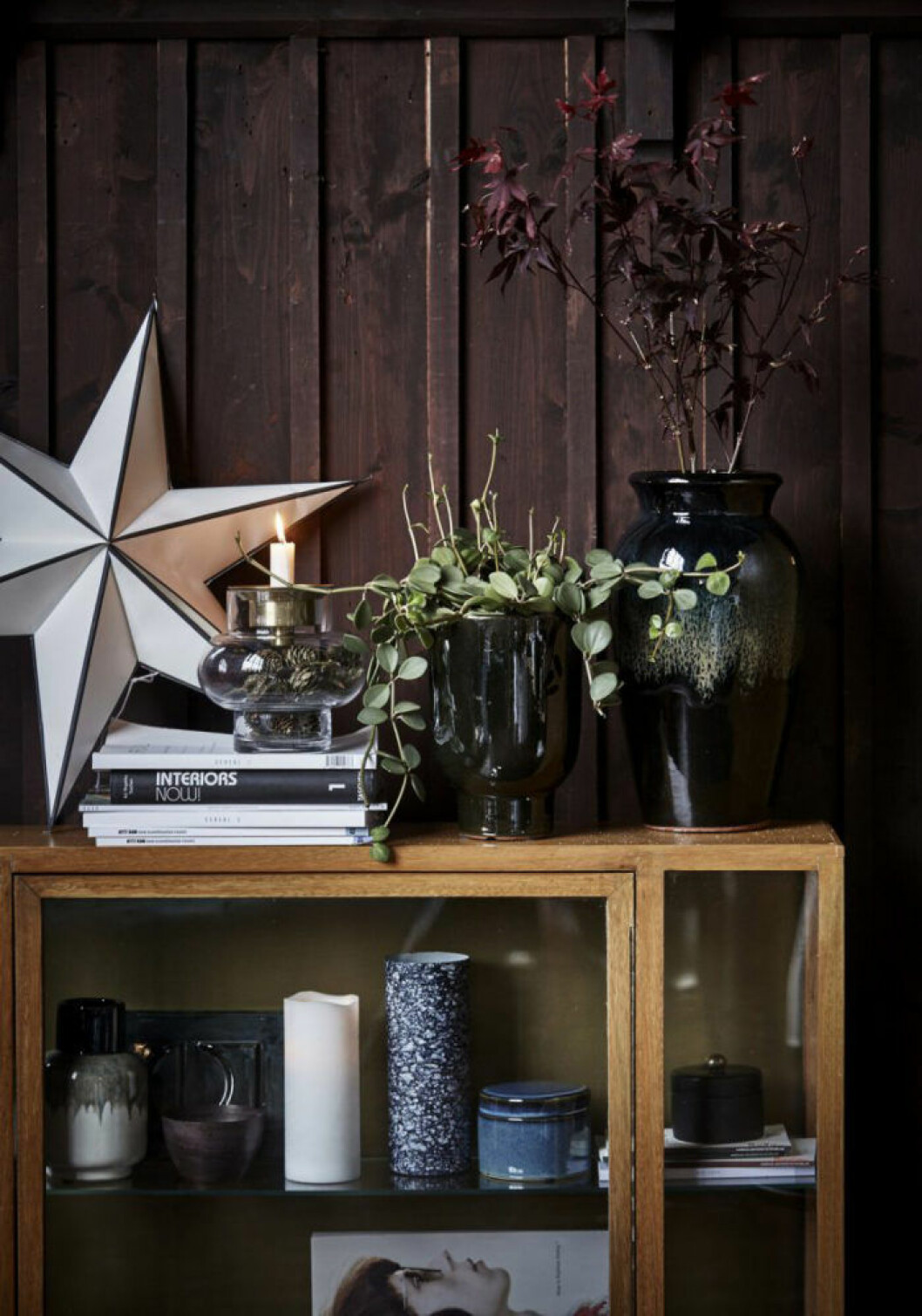 Foto: House Doctor Detaljbild på skåp med prydnadssaker i, en julstjärna placerad på.