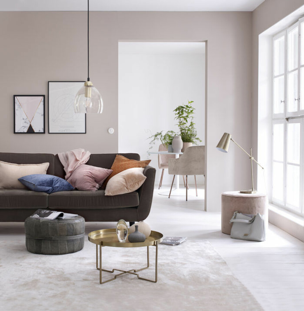Ljusrosa väggfärg, brun soffa, brickbord guld. Rosa sittpuff i sammet. Våren 2018 på Ellos Home.