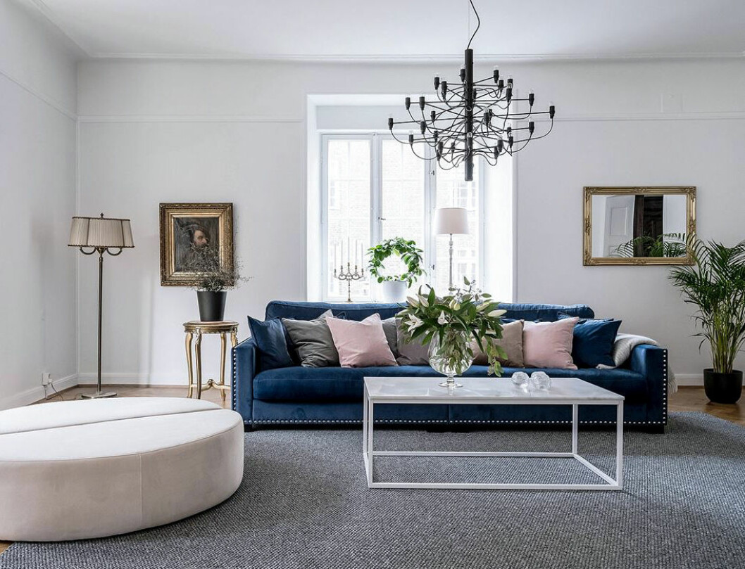 Foto: <a href="https://www.instagram.com/fotografalencordic/" target="_blank" rel="noopener">Alen Cordic</a>/SE360 Styling: <a href="https://www.instagram.com/by_boninterior/" target="_blank" rel="noopener">By Bon Interior</a> för <a href="https://www.instagram.com/bjurfors_goteborg/" target="_blank" rel="noopener">Bjurfors</a>/mäklare: Charlotta Lenhammar Rosa sittpuff och rosa kuddar. Flos takkrona och blå soffa i vardagsrummet.