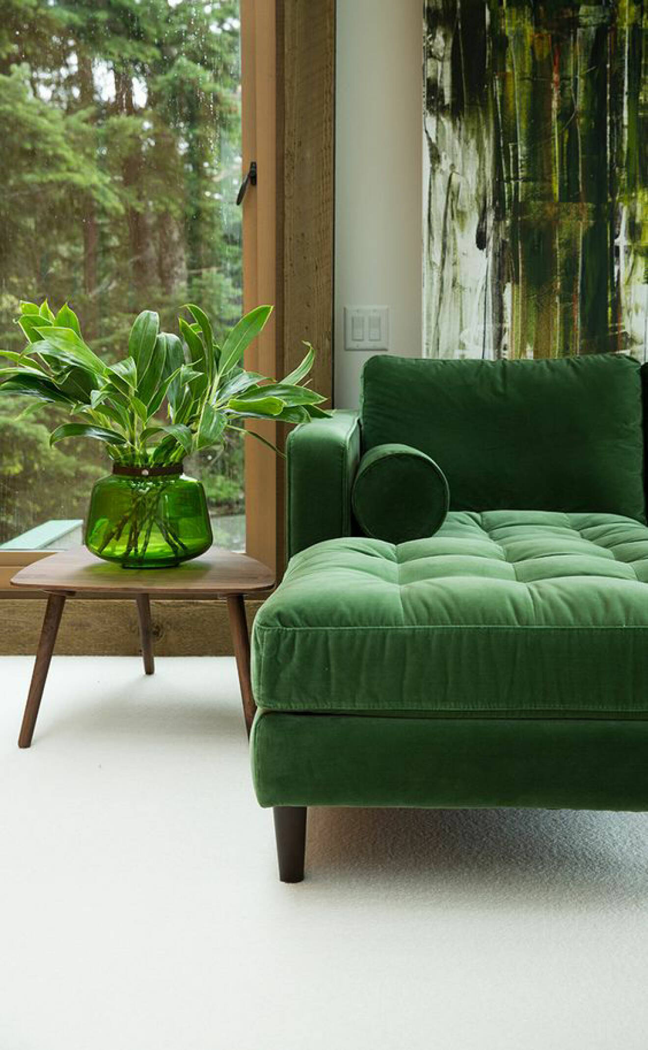 Grön soffa samt sidobord med grön vas