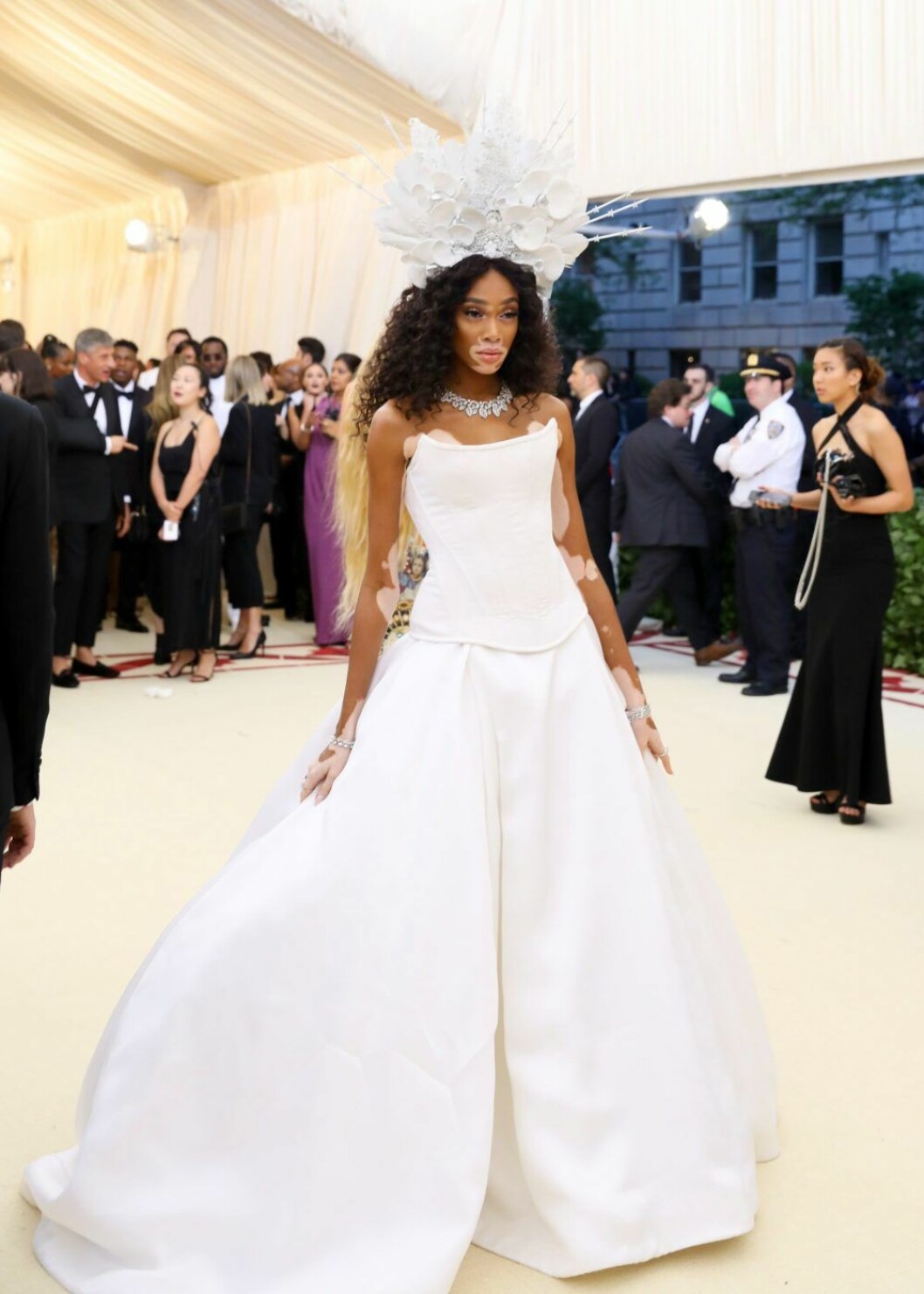 Winnie Harlow i vit klänning och maffig huvudbonad.