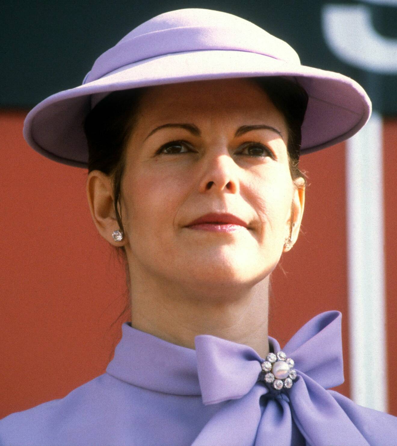 Drottning Silvia i lila hatt och matchande jacka.