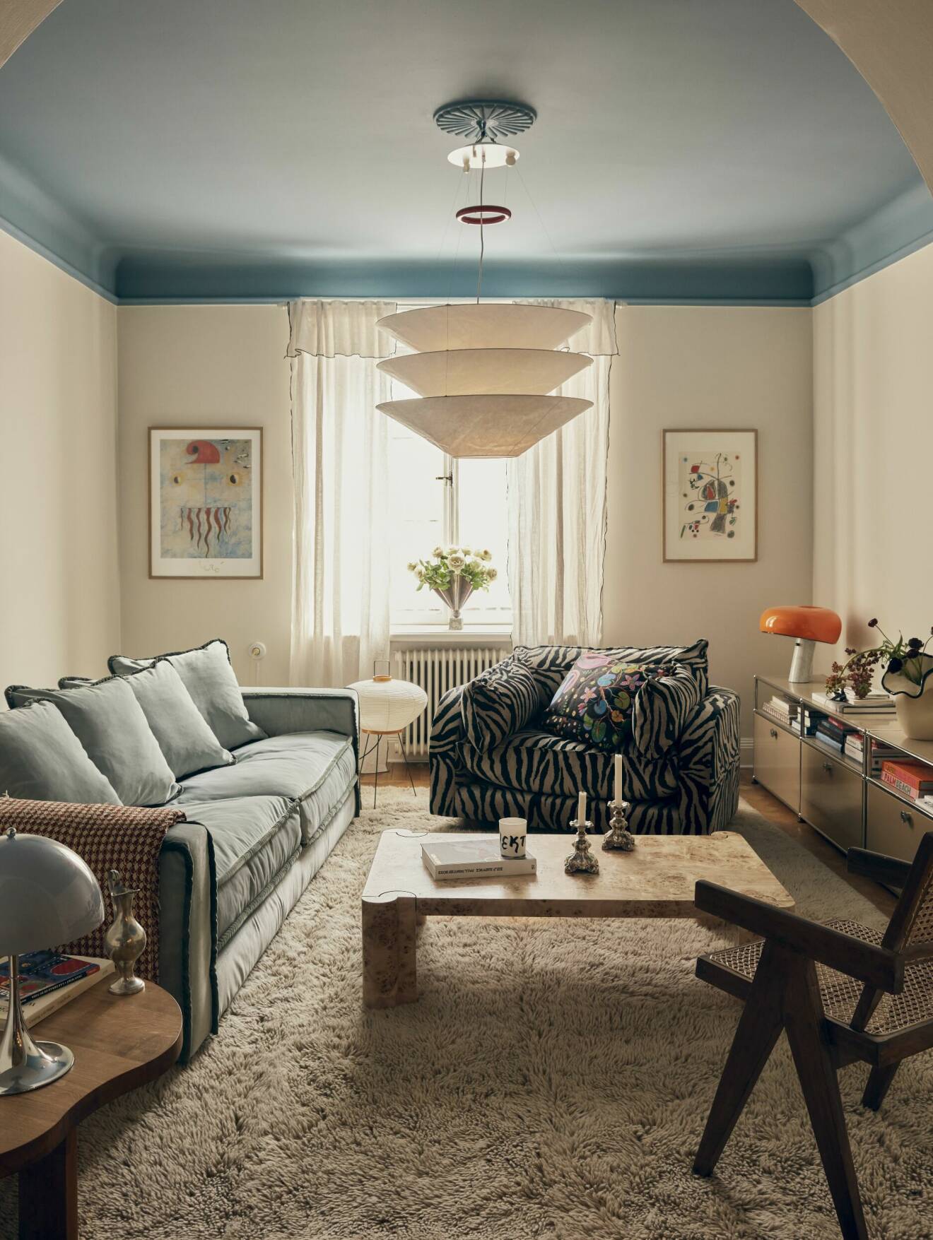 Vardagsrum med italiensk soffa och blåmålat tak
