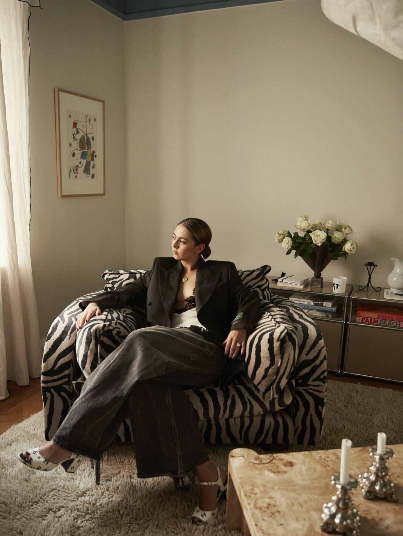 Hanna MW i zebramönstrad fåtölj i vardagsrummet med Miró-tavla från Palma