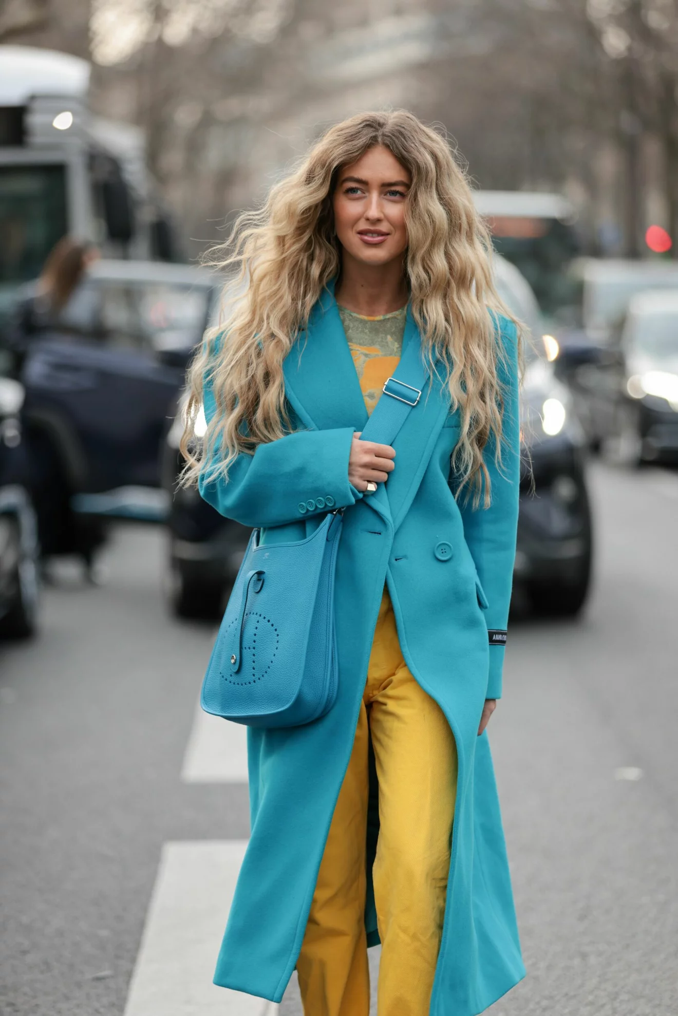 kvinna med blå kappa och gula byxor