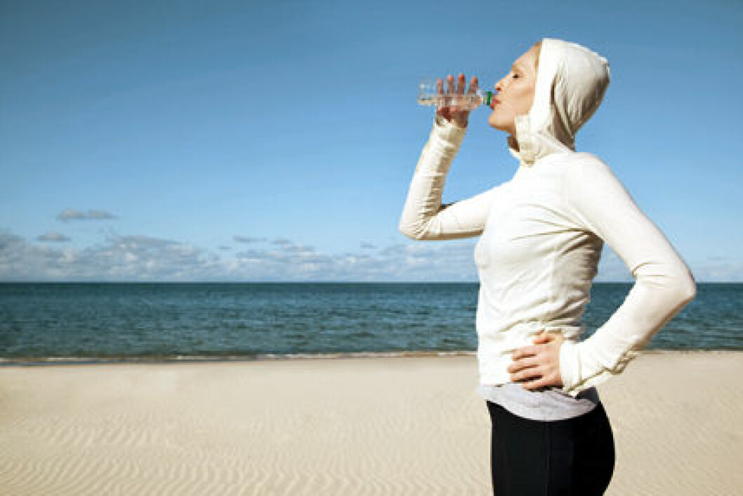 Female exercising and drinking water from bottle on Australian Beach