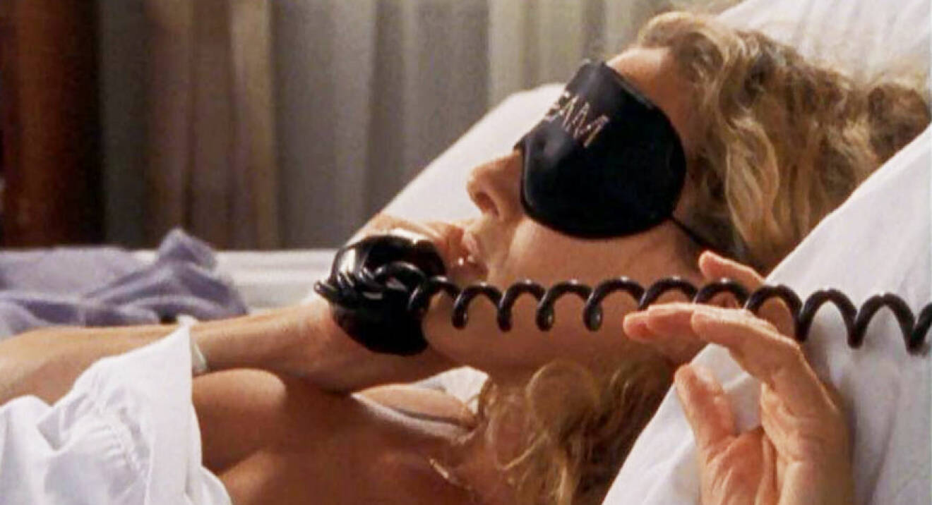 Carrie från Sex and the city pratar I telefon I sängen.