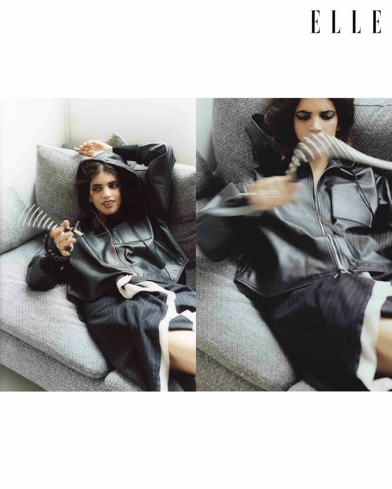 Modellen ligger i en soffa, hon har på sig en svart jacka med huva från Loewe, tillsammans med en svart kjol med vit kant från Dries van Noten