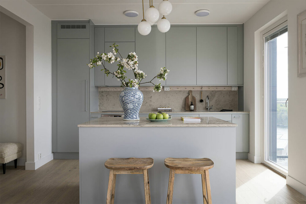 Intill köksön står barstolar i trä från Zara Home. Stilrent kök i blått