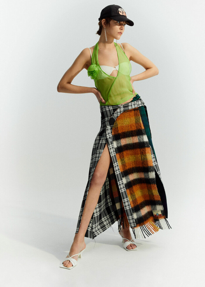 Modellen har på sig ett grönt linne från Saks Potts och en rutig kjol från Totême