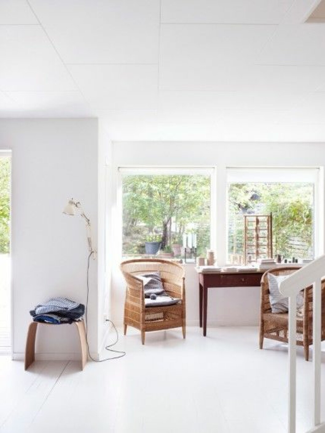 Familjen njuter av utsikten mot träden bakom huset. Korgstolar från African Touch. Pall <em>M,</em> design Jørgen Møller. arbetsplats-skrivbord-vitt-golv-inspiration-foto-anna-kern