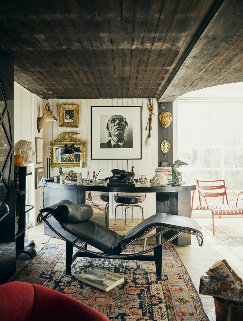 Porträttet av Hans gamla New York-kompis Andy Warhol kom till nästan i farten när de sprang på varandra på ett galleri i Stockholm. Chaiselongue LC4 av Le Corbusier, Pierre Jeanneret och Charlotte Perriand för Cassina, fyndad i grannbyn. Skrivbordet, från en loppis på Södermalm, sägs ha tillhört Bibi Andersson. Strindberg på väggen är lite av en husgud. Precis som Hans såg han omen och symboler överallt. ”Spelkort har jag ofta med i mina stilleben. De måste innehålla en gåtfullhet, annars är de bara en snygg illustration.” På väggen finns även påven. ”Jag målade honom när han sitter på en Gustavsbergstoalettstol. Titeln är Påven spolar kvinnliga präster.” Arbetsrum