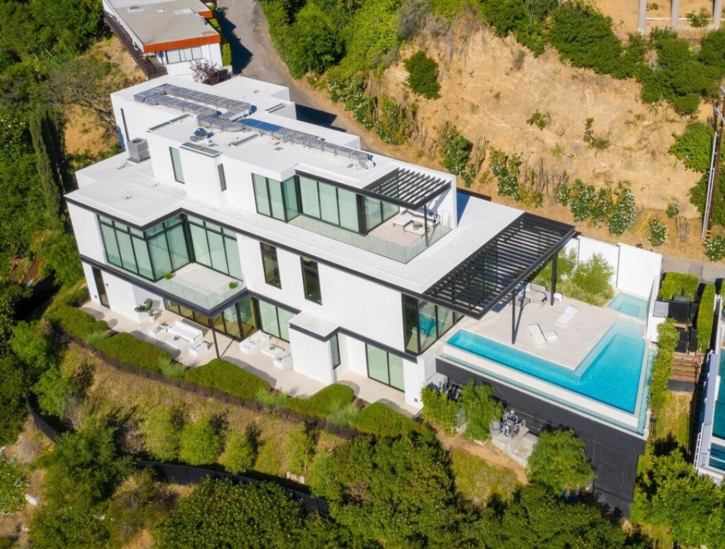 ett stort hus i vitt och glas med en pool utanför. 