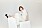 Fotomodellen sitter på sidan, hon har på sig en vit topp med ett vitt linne och vit kjol, allt från Bottega Veneta.