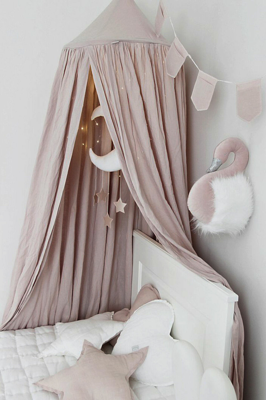 Foto via: <a href="https://istome.co.uk/products/linen-canopy-powder-pink" target="_blank" rel="noopener">Istome</a> Ljusrosa sänghimmel med ljusslinga