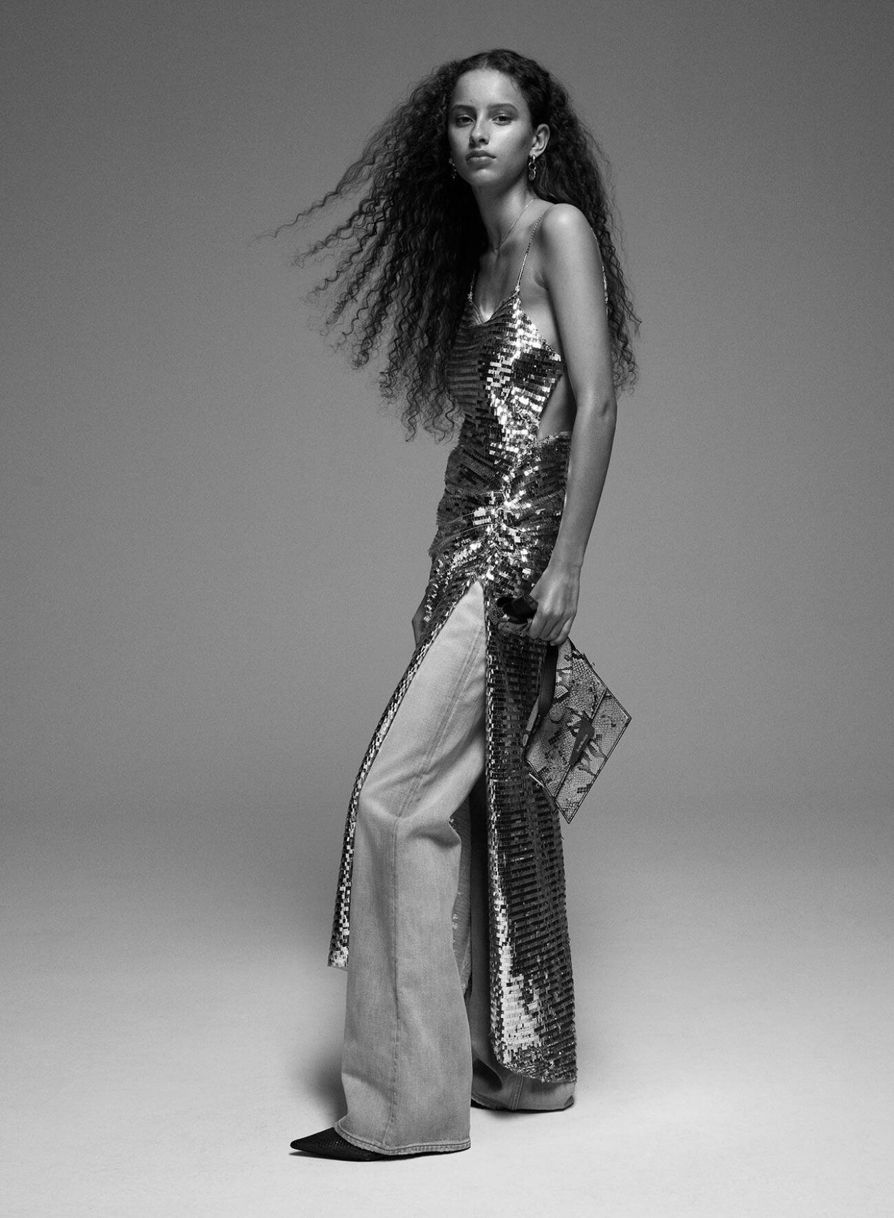 Modellen har på sig en glittrig klänning från Jade Cropper över jeans från Acne Studios