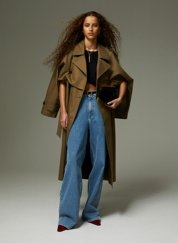 Trenchcoat, 8 300 kr, Totême/Mytheresa. Topp, 1 900 kr, House of Dagmar. Jeans, 3 600 kr, BITE. Väska, 23 000 kr, och skärp, 4 350 kr, båda Celine by Hedi Slimane. Skor, 4 200 kr, Totême. Halsband, 4 700 kr, Saint Laurent by Anthony Vaccarello. Örhänge, 1 400 kr, Acne Studios. Modellen bär en trenchcoat från Totême med en svart topp under från House of Dagmar samt ljusblå jeans från BITE