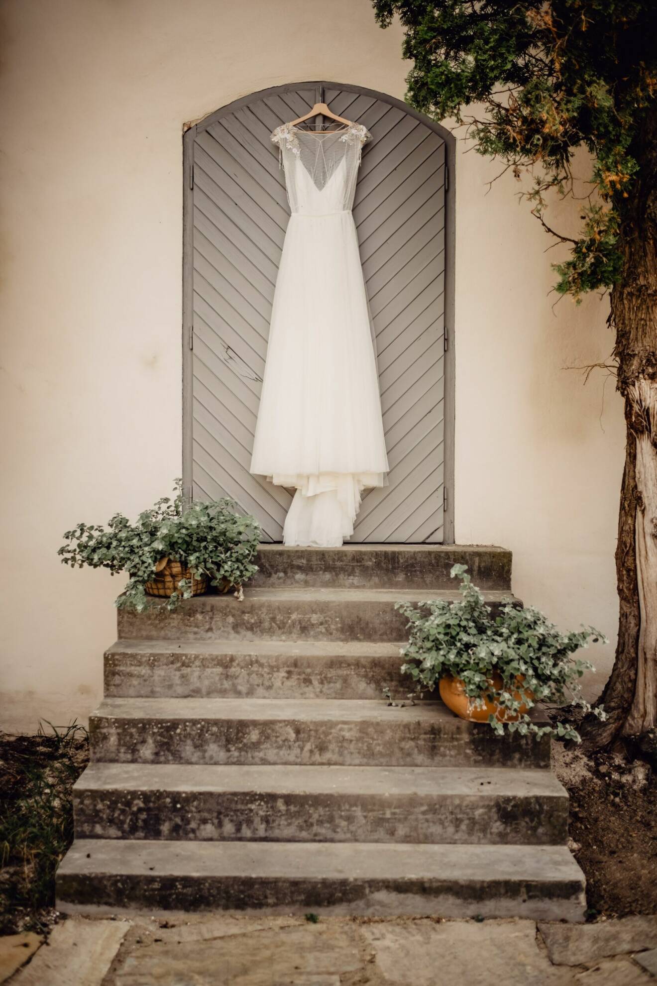 bröllopsklänning som hänger på en dörr framför en stentrappa