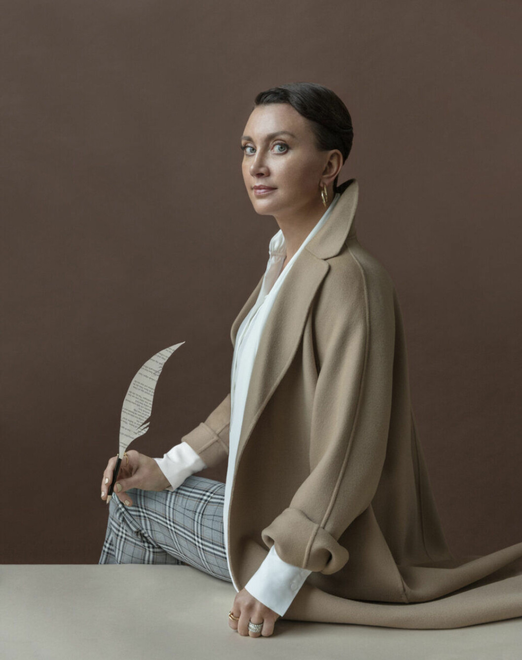 Kappa, Max Mara. Blus, Tiger of Sweden. Byxor, Hope. Örhänge, Acne Studios. Ring med bollar, Sophie by Sophie/NK Access. Spikring, Cartier. Camilla Läckberg i kamelfärgad kappa från Max Mara