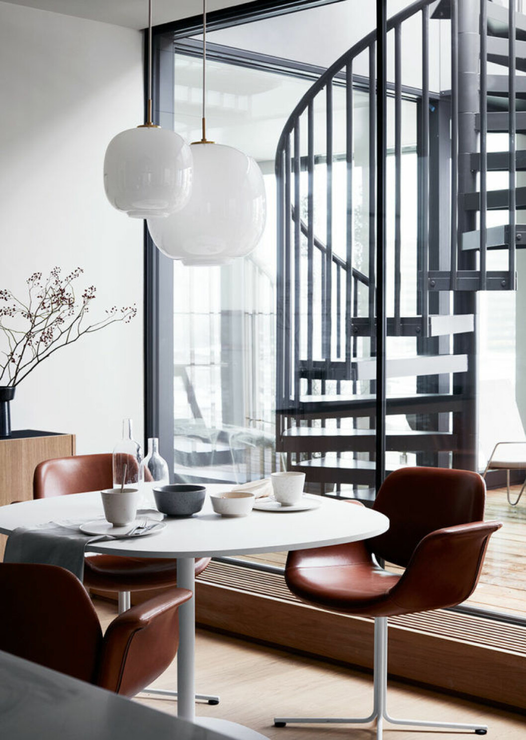 Bekväm matplats med bord och stolar från Erik Jørgensen. Keramiken Ombria kommer från Kähler, bestick från Kay Bojesen och bordslinne från Georg Jensen Damask. I bakgrunden skymtar  den skulpturala spiraltrappan som leder upp till takterrassen.