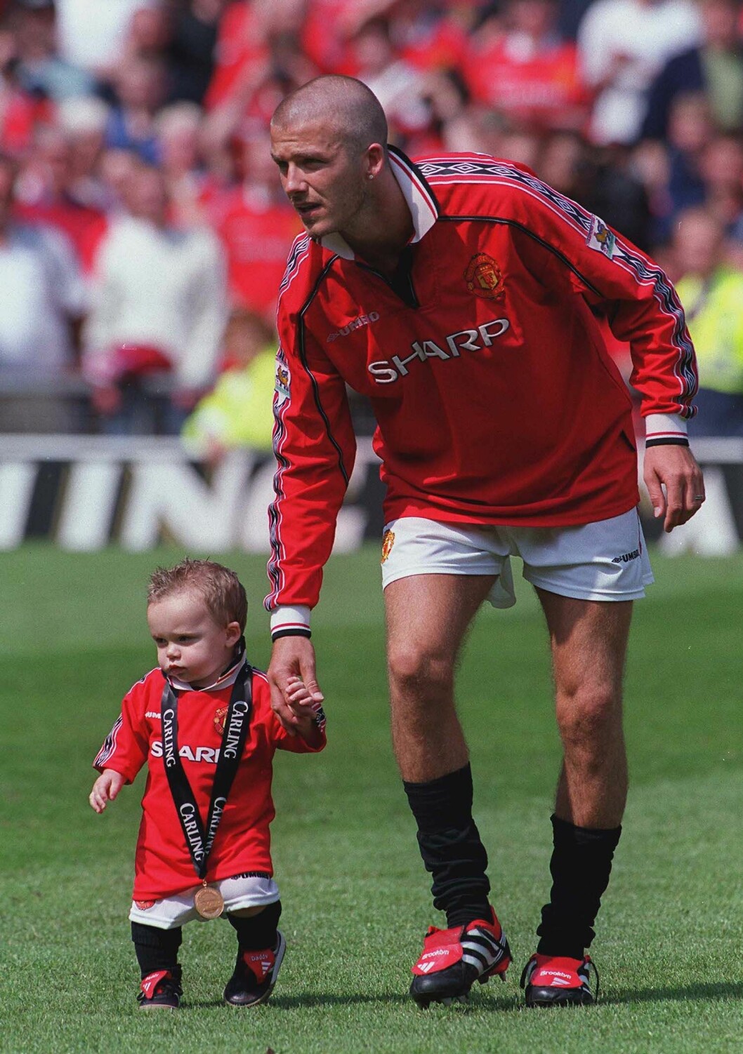 David Beckham håller lilla Brooklyn Beckham i handen