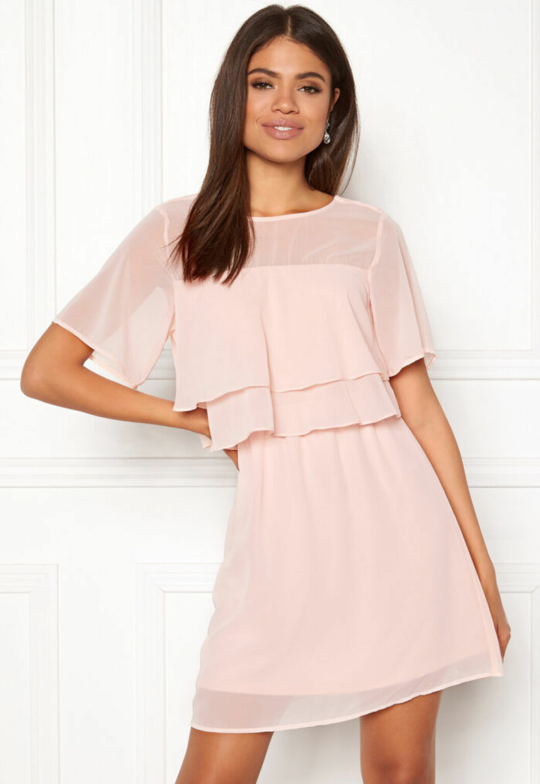 En bild på en pastellrosa klänning med volangdetaljer från Vero Moda.