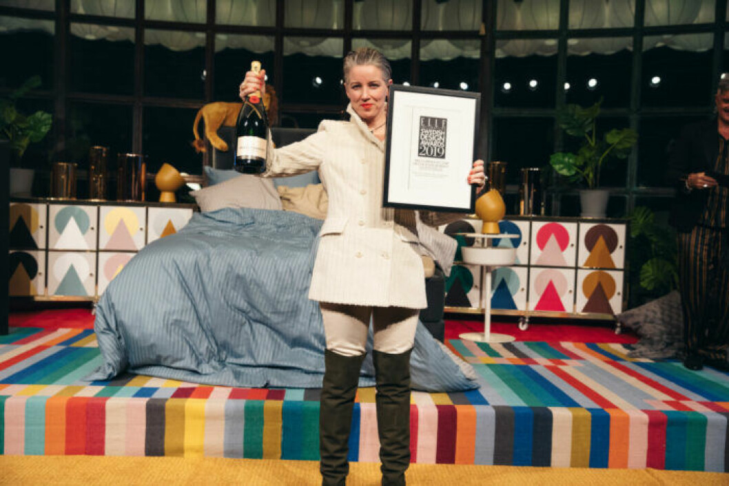 Glad vinnare på scen iklädd vit outfit på ELLE Decoration Swedish Design Awards 2019