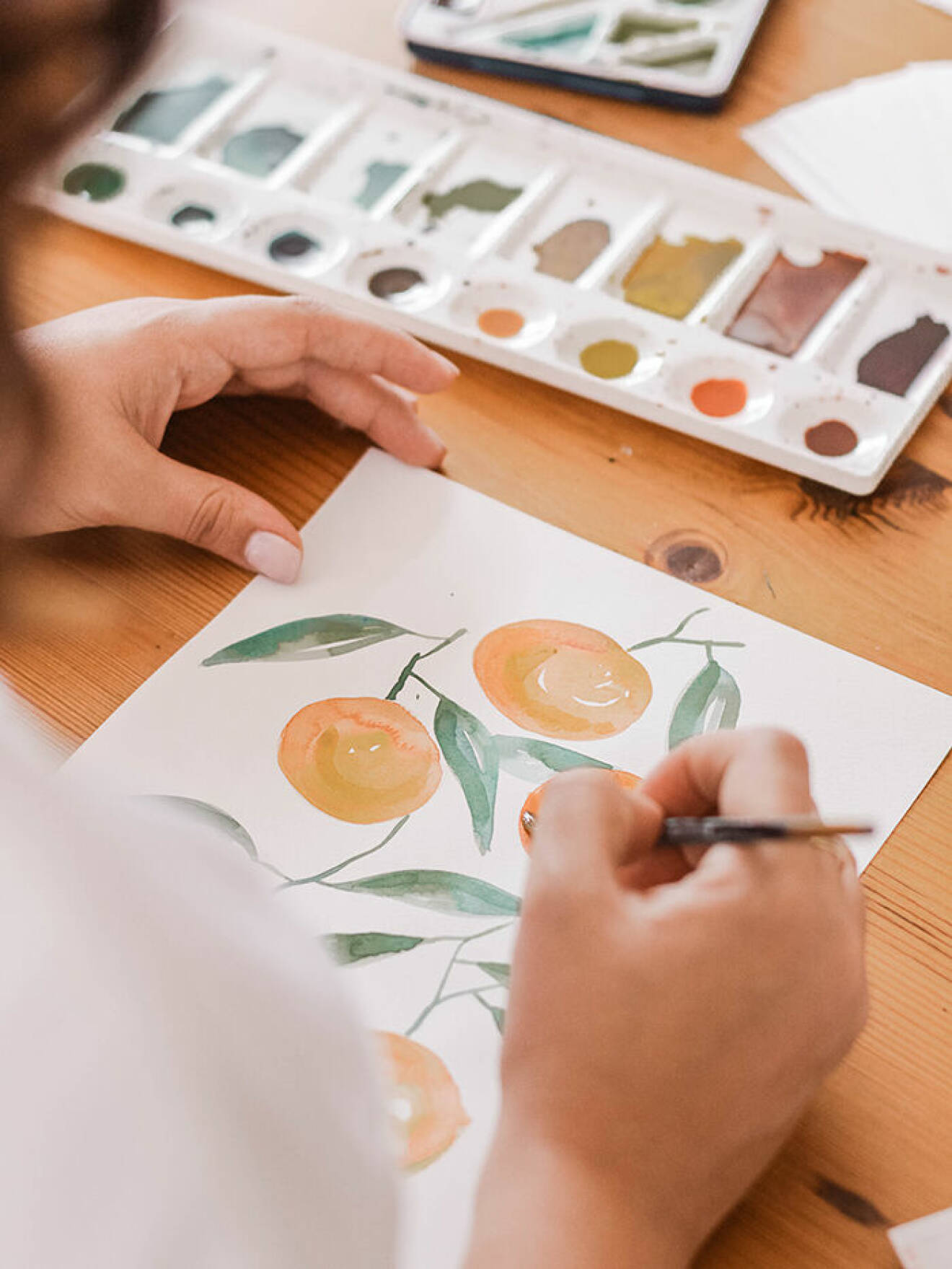 en kvinna som målar apelsiner med akvarell