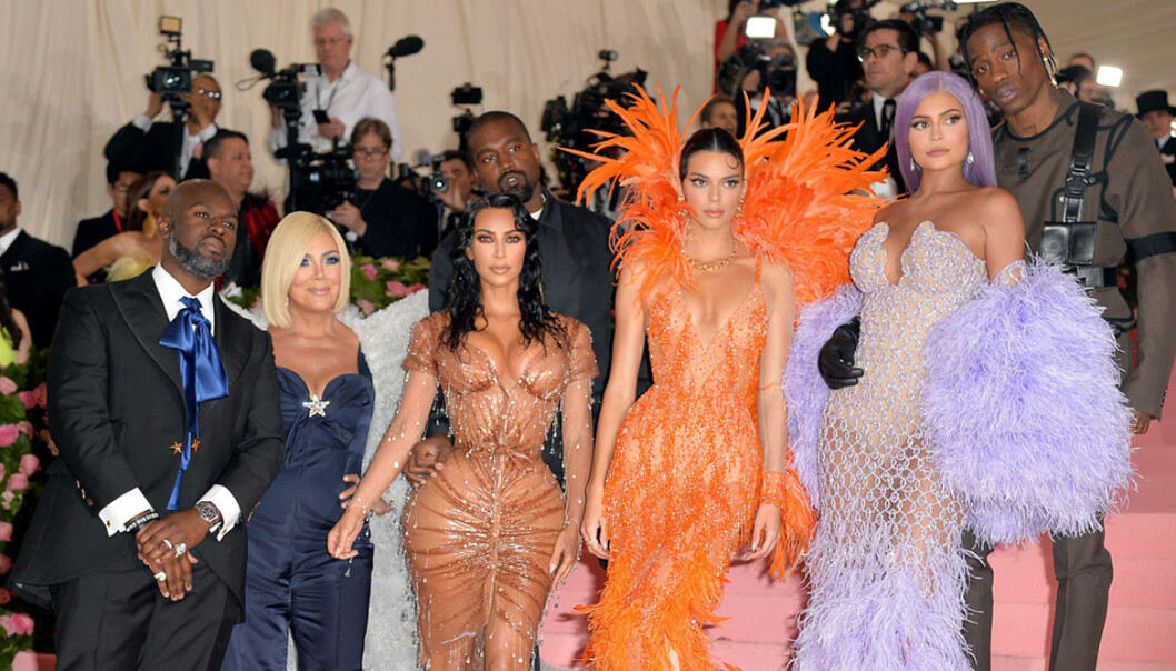 Familjen Kardashian/Jenner står i en trapp och blir fotade av massa paparazzifotografer