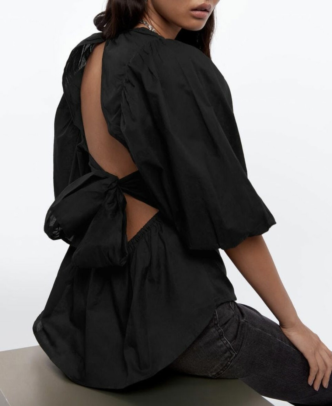 Svart blus med dekorativ rosettdetalj i ryggen från Gina tricot.