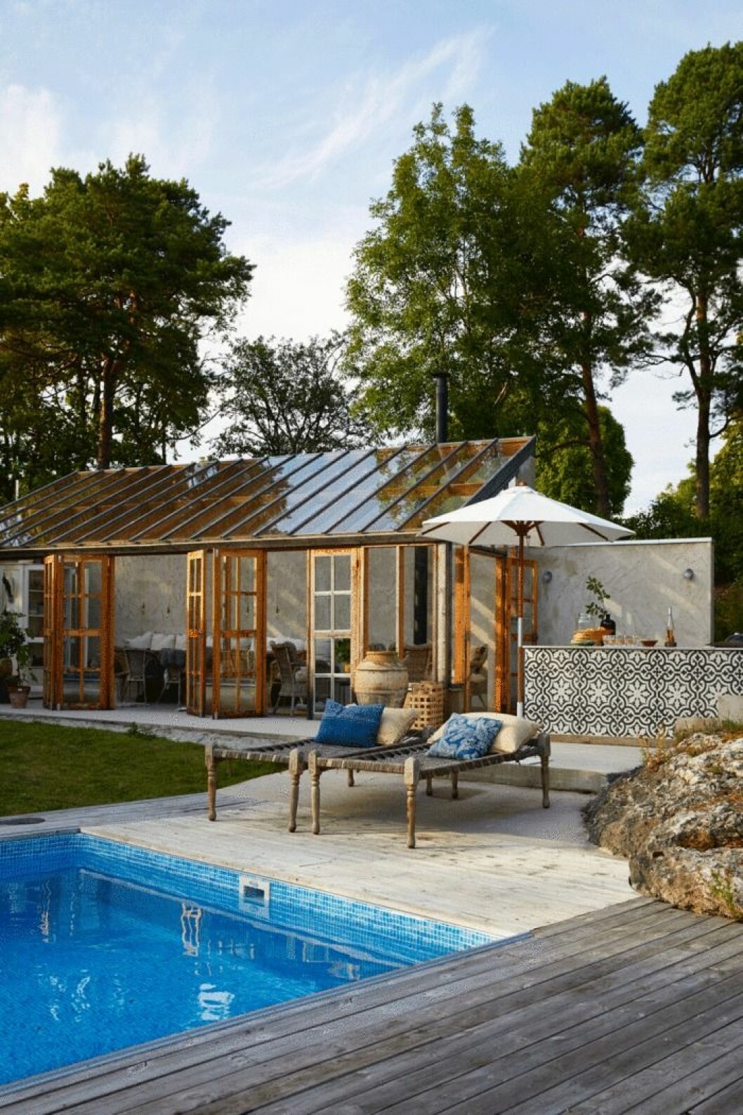 Solsängarna fick Lotta Noremark köpa av en kollega och kruka har hon släpat hem från Mallorca. Kuddarna kommer från Kvarnbacken Inredning i Ljugarn. Huset är byggt av Nife Entreprenad. Pool utanför glasverandan