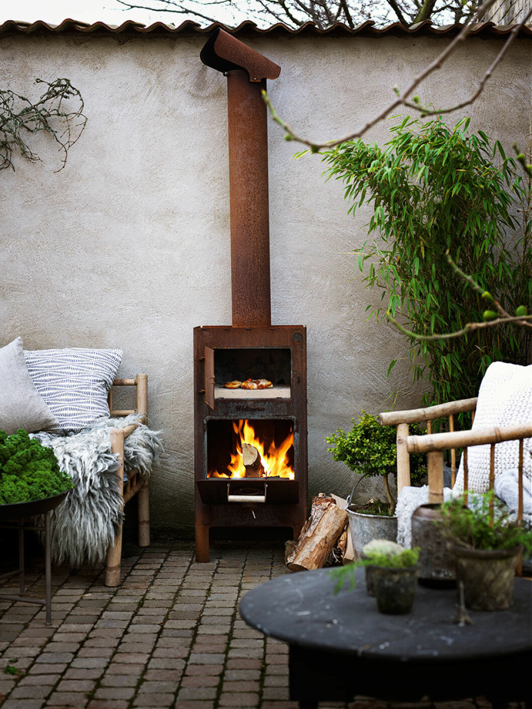 Soffa och fåtölj, Tine K Home, kamin från Weltevree. Soffbord i trä, Sidsid, soffbord i metall, PB Home.