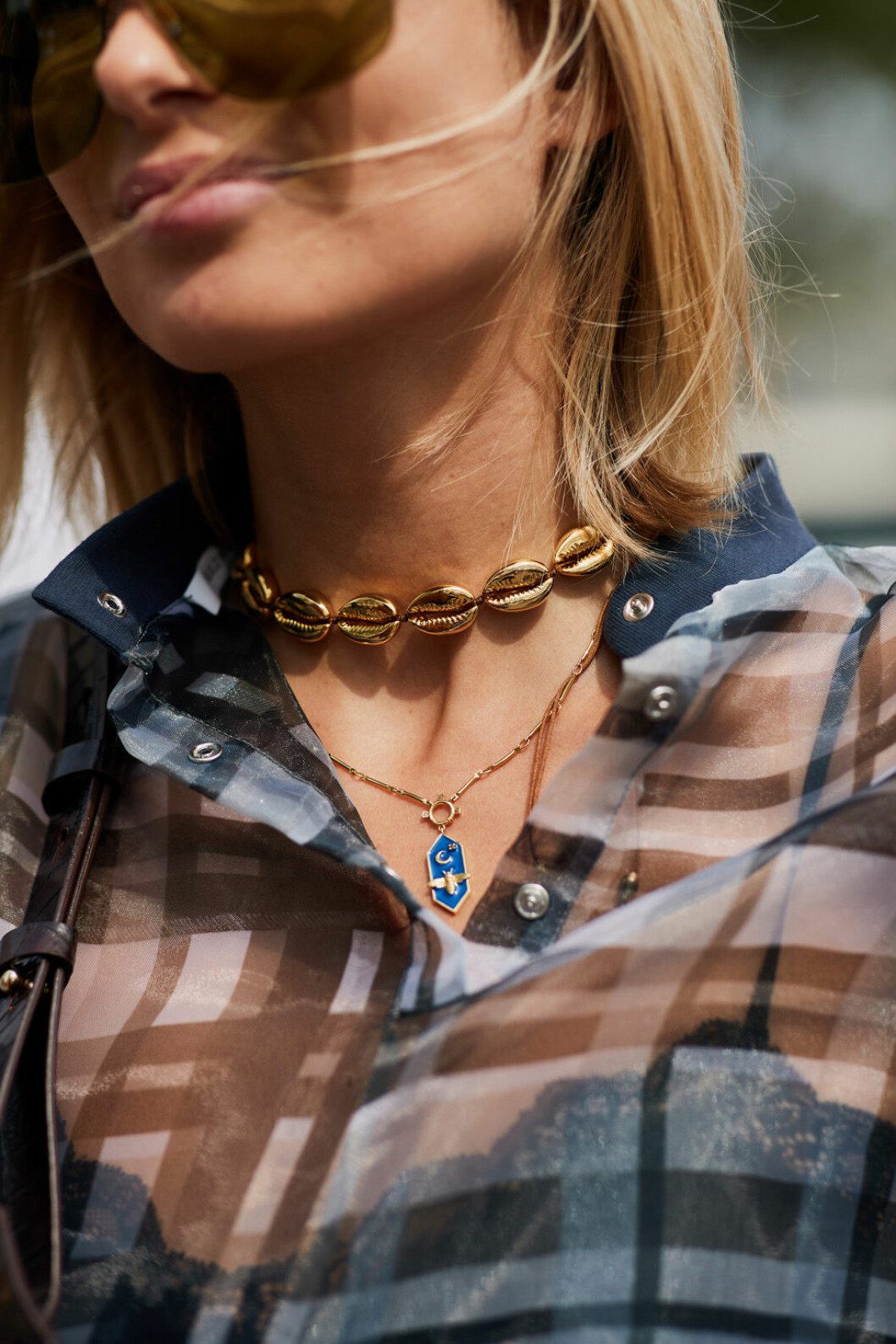 Tjej i rutig blus och fina halsband. Snäckhalsband i gul.