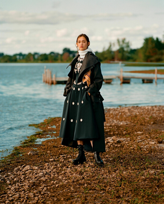 Jacka, 7 500 kr, Coach. Klänning, pris vid förfrågan, Erdem. Boots, 2 800 kr, Michael Kors. Huva, stylistens egna. Modellen har på sig en svart lång jacka från Coach, en mörkgrön klänning från Erdem och en vit huva