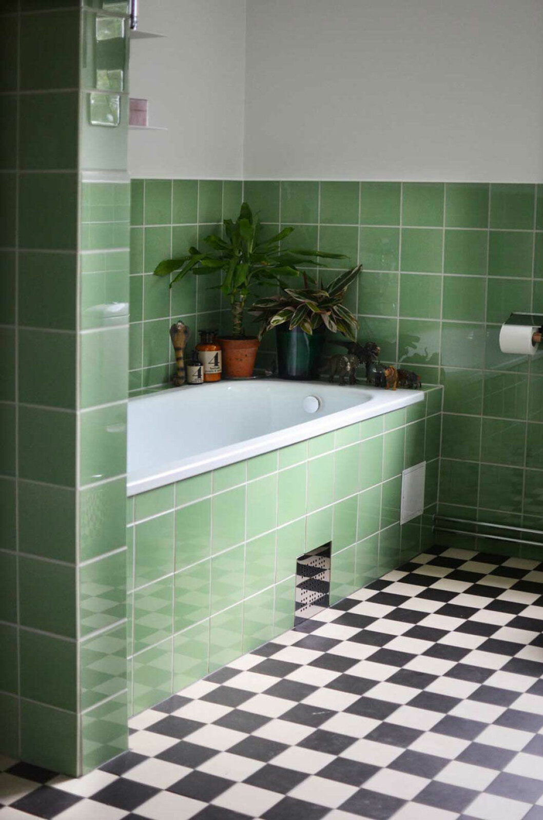 När badrummet renoverades ville Helena och hennes partner framställa något i stil med resten av huset. Badrummet är halvkaklat i grönt kakel, svartvit rutigt klinkergolv, platsbyggt badkar och ljuvliga keramiksocklar på lamporna. Helkaklat badrum i grönt