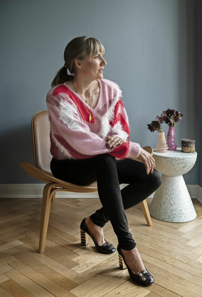 Kirstine sitter i en <em>Shell chair</em> av Hans J. Wegner. Sidobordet är tillverkat av återvunnen plast, Wild Studio.