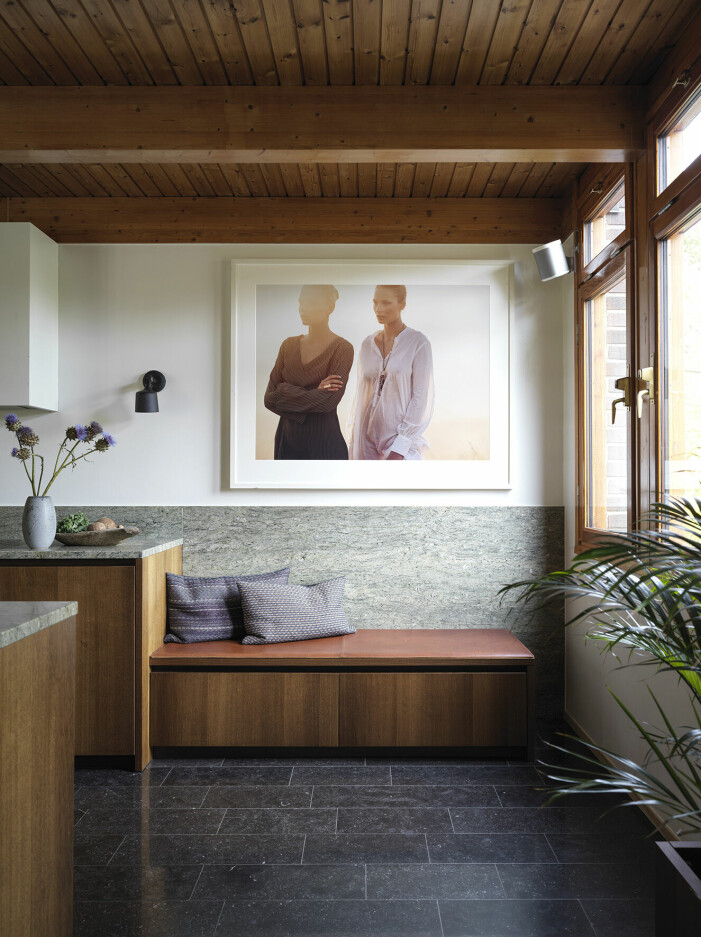 Köket är platsbyggt och kommer från Kvänum, deras <em>Intro</em>. Ovanför kökssoffan ett fotografi av Andreas Kock, från en moderesa där Emma var stylist. Golvet av belgisk granit är nylagt. Köket är platsbyggt och det svarta golvet är belgisk granit