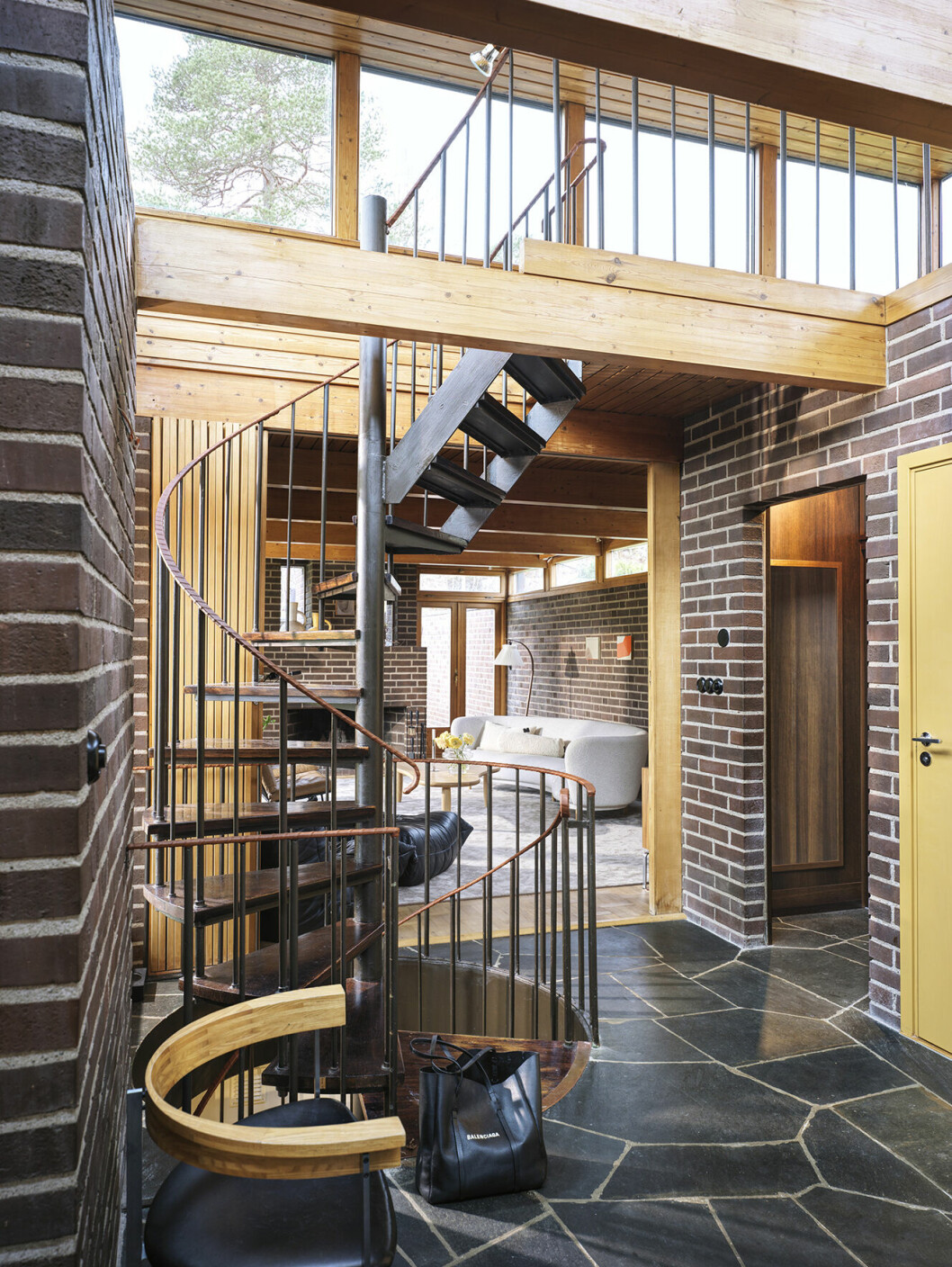 Spiraltrappan går från souterrängplan upp till lanterninen som skapar ljusflödet i hallen. Skiffergolvet är original från när huset byggdes, men täcktes av parkett när Emma och Nils flyttade in. Spiraltrappan från souterrängplan upp till lanterninen skapar ljusflöde i hallen