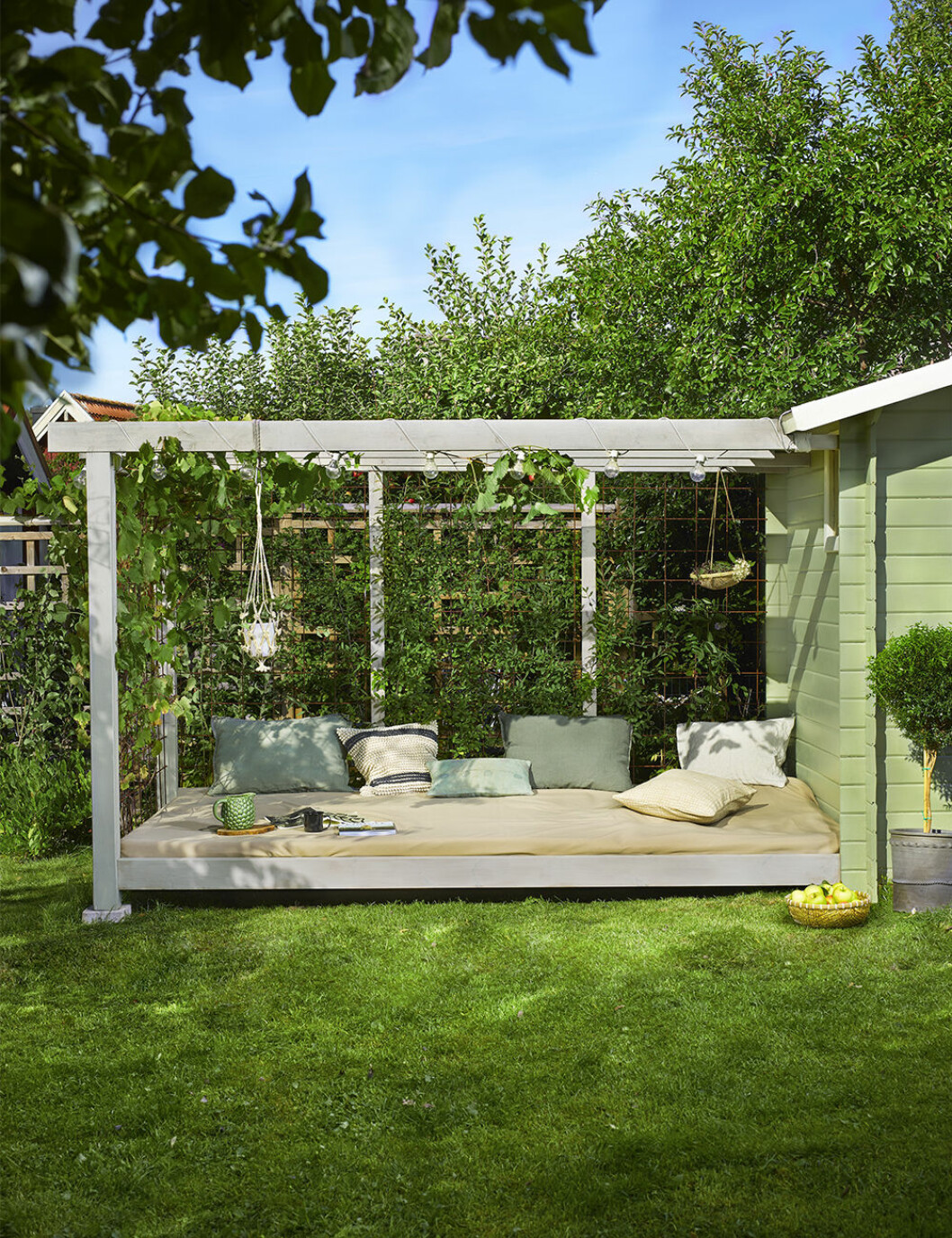 Måla om utomhus! Pergolan är målad med trälasyr i kulören <em>Halm 9234</em>, fasaden går i färgen <em>Park 085</em>. Foto: Beckers Pergola med mysig solbädd